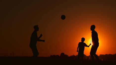 Drei-Jungen-Spielen-Bei-Sonnenuntergang-Fußball.-Silhouette-Von-Kindern,-Die-Bei-Sonnenuntergang-Mit-Einem-Ball-Spielen.-Das-Konzept-Einer-Glücklichen-Familie.